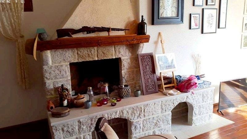 Karadağ, Krimovice’deki villanın iç mekanında doğal taş şömineli oturma odası: dekor, ahşap raf ve sıcak bir atmosfer.