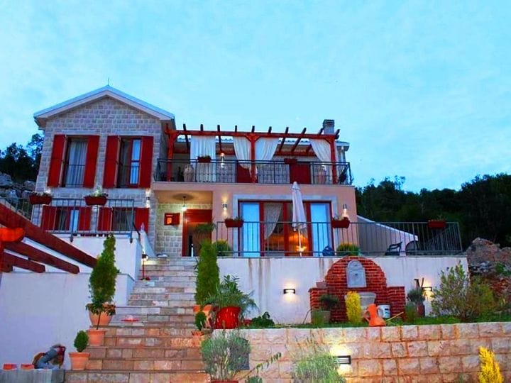 Karadağ, Krimovitsa’da teraslı, kırmızı panjurlu ve peyzaj düzenlemesi yapılmış arsaya sahip iki katlı taş villa.
