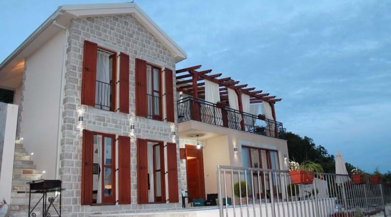 Krymoviçe, Karadağ’da teraslı ve ahşap kepenkli iki katlı taş villa, akşam dış görünüm.