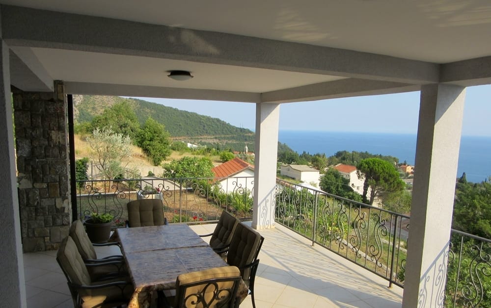 Spacieuse terrasse de la villa à Reževići, Monténégro, avec coin repas, garde-corps en fer forgé et vue panoramique sur la mer.