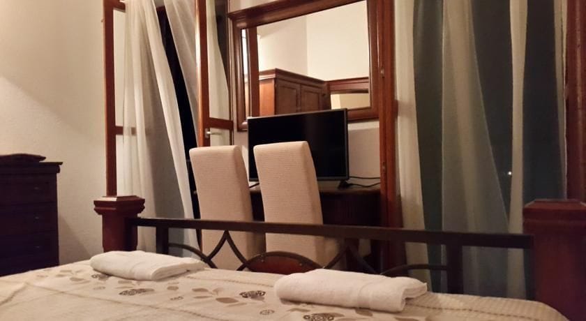 Karadağ, Krimovitsa’daki villada ahşap yatak, TV ve aynalı уютlu yatak odası. Yumuşak mobilyalı iç mekan.