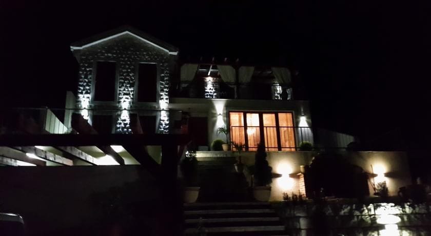 Karadağ, Krimovitsa’daki iki katlı villa: cephenin gece aydınlatması, taş kaplama ve panoramik pencereli teras.