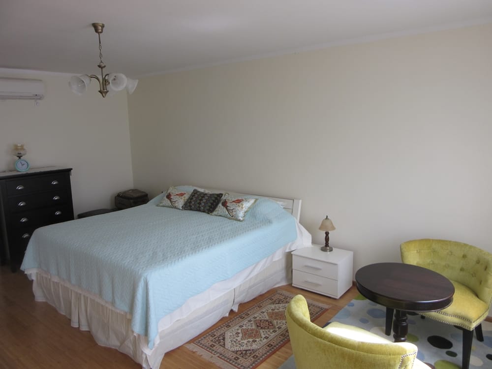 Chambre confortable avec lit double et coin salon dans une villa à Reževići, Monténégro : intérieur lumineux et mobilier.