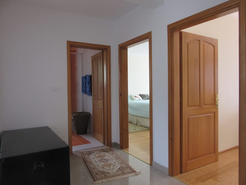 Entrée avec portes en bois et vue sur la chambre dans une villa, Reževići, Monténégro. Intérieur lumineux avec tapis.