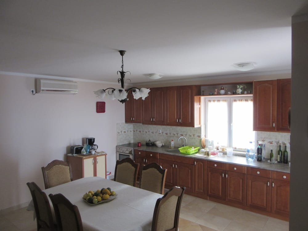 Cuisine avec mobilier en bois et coin repas dans une villa à Reževići, Monténégro : intérieur avec climatisation et mobilier.