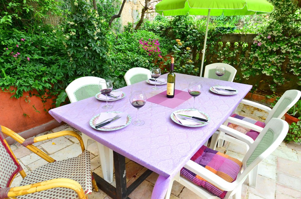 Gedeckter Esstisch in einem gemütlichen grünen Garten eines Hauses in Herceg Novi, Montenegro, zum Entspannen im Freien.