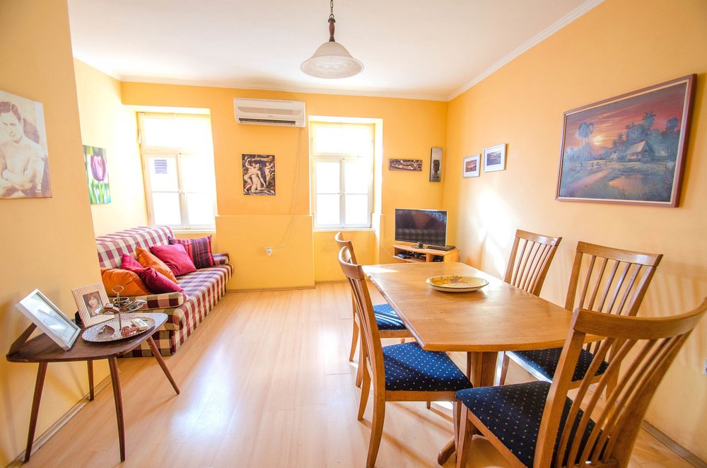 Wohnzimmer mit Essbereich in einem Haus in Herceg Novi, Montenegro: heller Raum mit Sofa, Tisch und Klimaanlage.