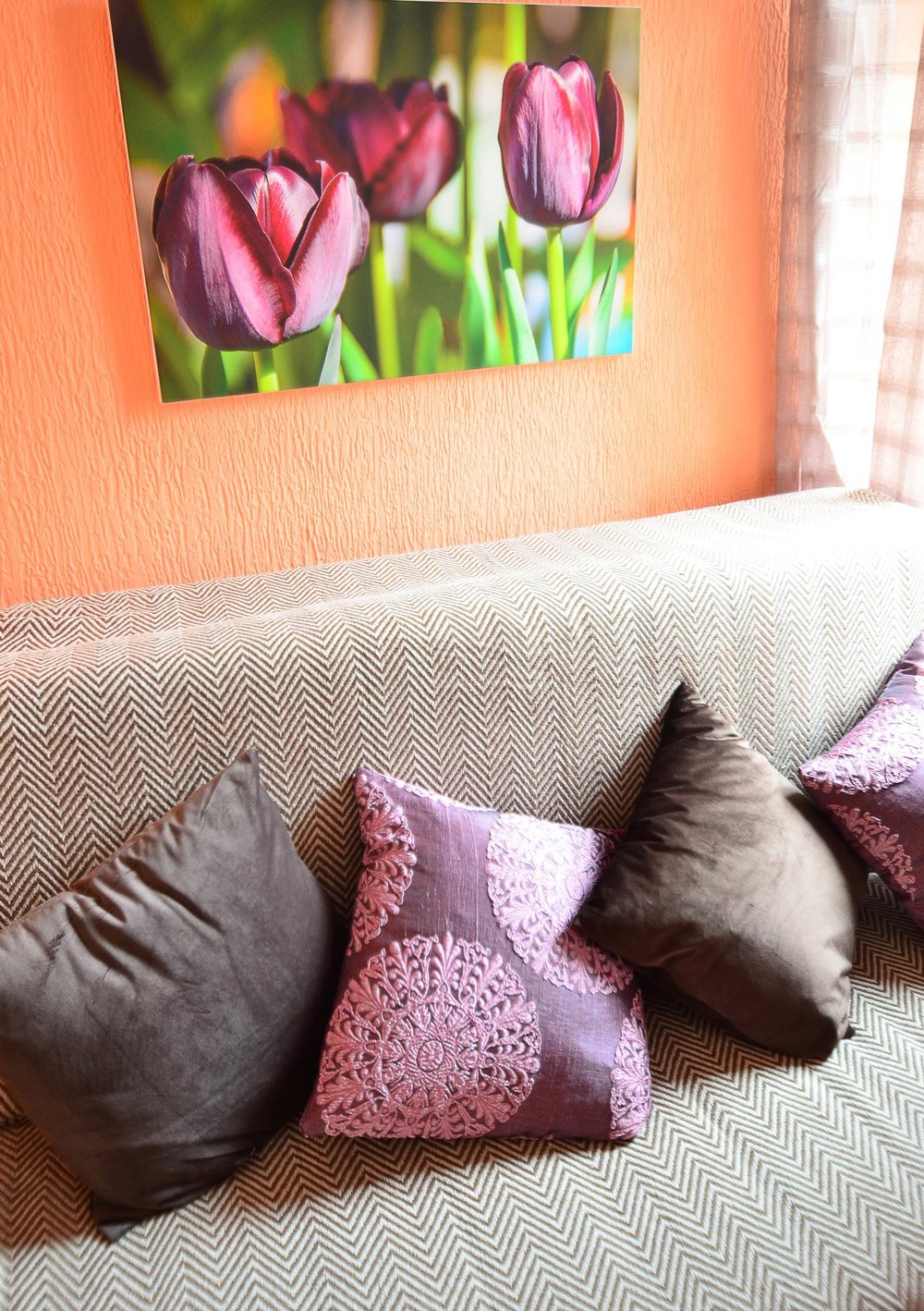 Gemütliches Wohnzimmer in einem Haus in Herceg Novi, Montenegro: Sofa mit dekorativen Kissen und ein Bild mit Tulpen an der Wand.