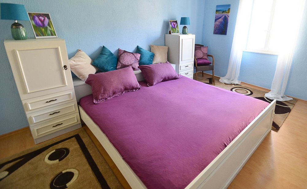 Gemütliches Schlafzimmer mit Doppelbett in einem Haus zum Verkauf in Herceg Novi, Montenegro: helle Möbel und blaue Wände.