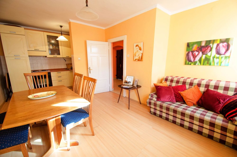 Wohnzimmer mit Essbereich und Küche in einem Haus in Herceg Novi, Montenegro: helle Möbel, karierter Sofa und Laminat.