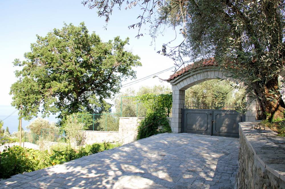 Karadağ, Budva Rivierası, Reževići’deki evin taş kemerli ve kapılı girişi, zeytin ağaçlarıyla çevrili.