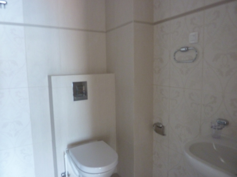 Savremeno kupatilo sa visećom WC šoljom i svetlim pločicama u stanu u Pržnu, Crna Gora.
