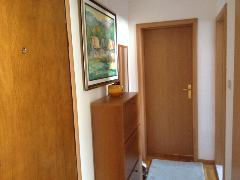 Heller Flur in einer Wohnung in Budva, Montenegro: Holzmöbel, Innentüren und ein Bild an der Wand.