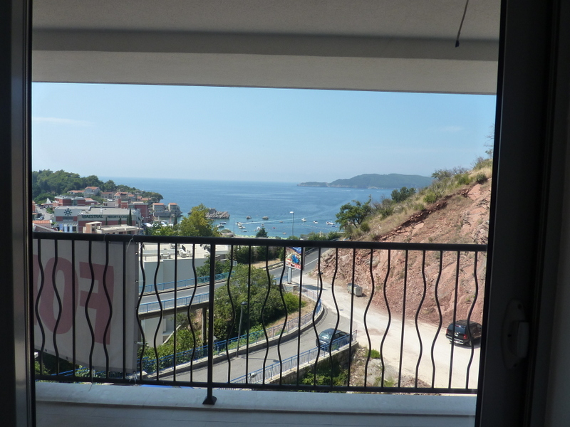 Pogled s balkona stana u Pržnu, Crna Gora: panorama Jadranskog mora, hotel Maestral i planinski pejzaž.