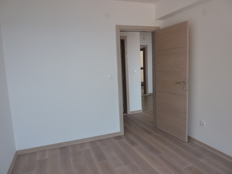 Svetla dnevna soba sa laminatom i unutrašnjim vratima u novom stanu u Pržnu, Crna Gora. Savremena završna obrada.