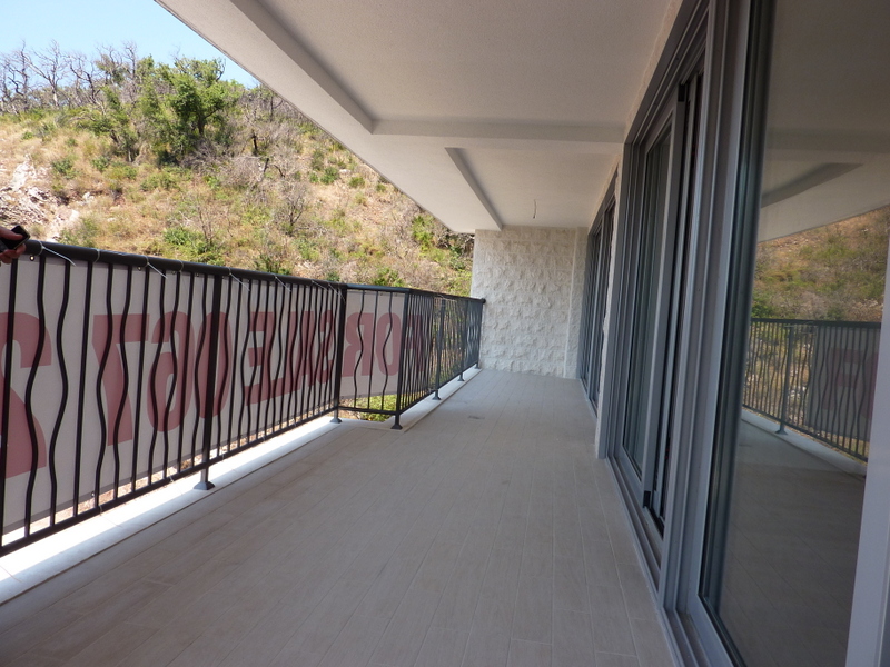 Prostran balkon s panoramskim pogledom na planine u stanu u Pržnu, Crna Gora: moderna završna obrada i ograda.