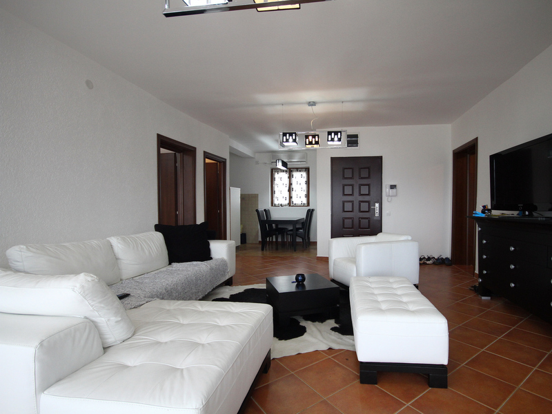 Helles Wohnzimmer mit weißen Ledermöbeln in einer zum Verkauf stehenden Wohnung in Bečići, Montenegro: modernes Interieur mit TV-Bereich.