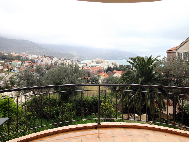 Blick vom Balkon der Wohnung in Bečići, Montenegro: Panorama auf Stadt, Berge und Meer, Fliesenbelag, schmiedeeisernes Geländer.