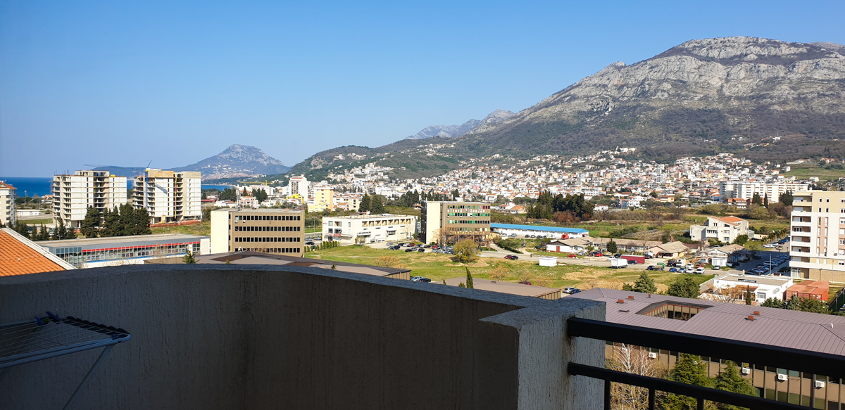 Pogled s balkona stana u gradu Bar, Crna Gora: panorama grada, planinski pejzaž i morska obala u daljini.