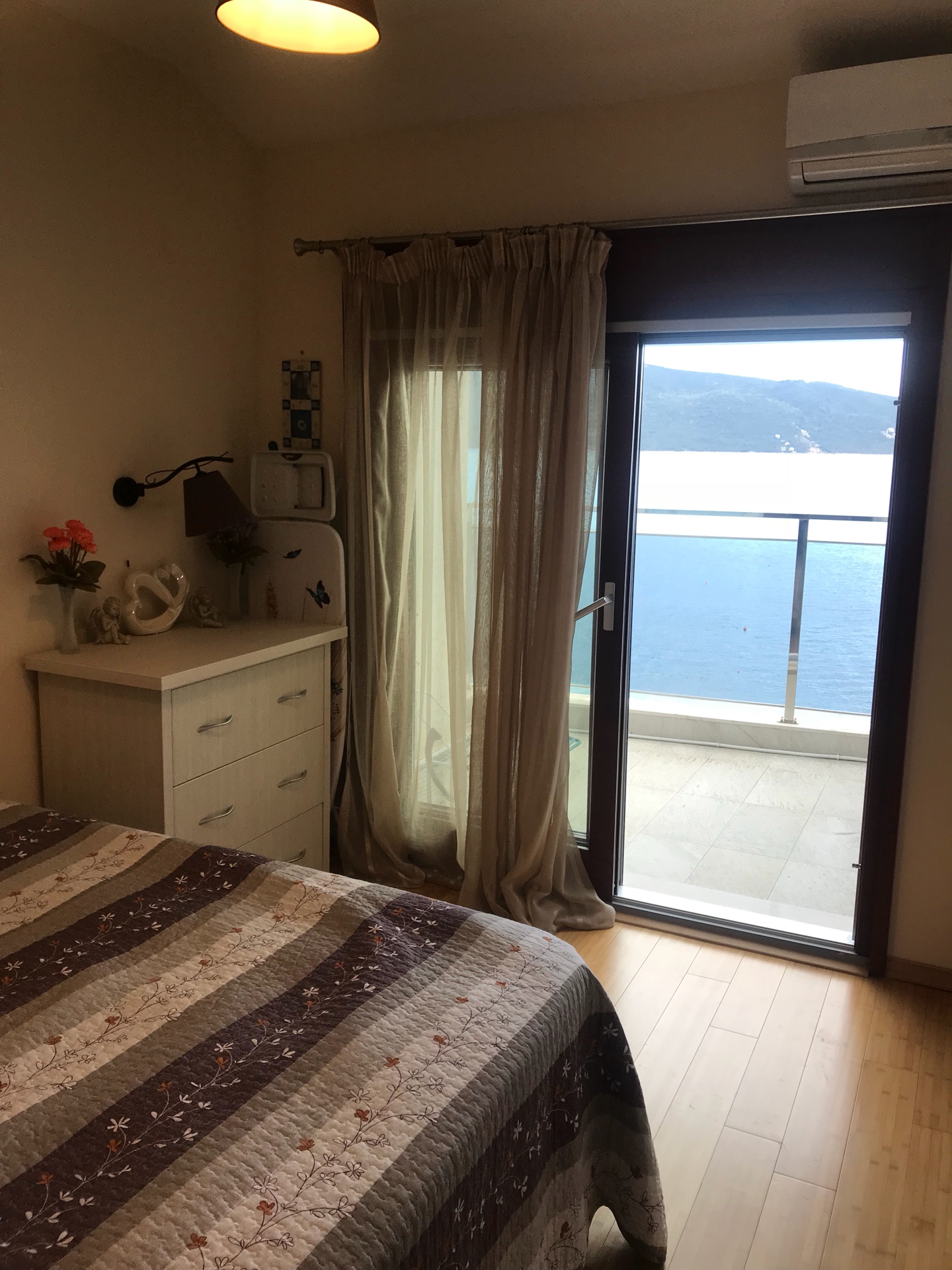 Sypialnia w mieszkaniu w Herceg Novi, Czarnogóra: widok na morze z balkonu, jasne meble i przytulne wnętrze.