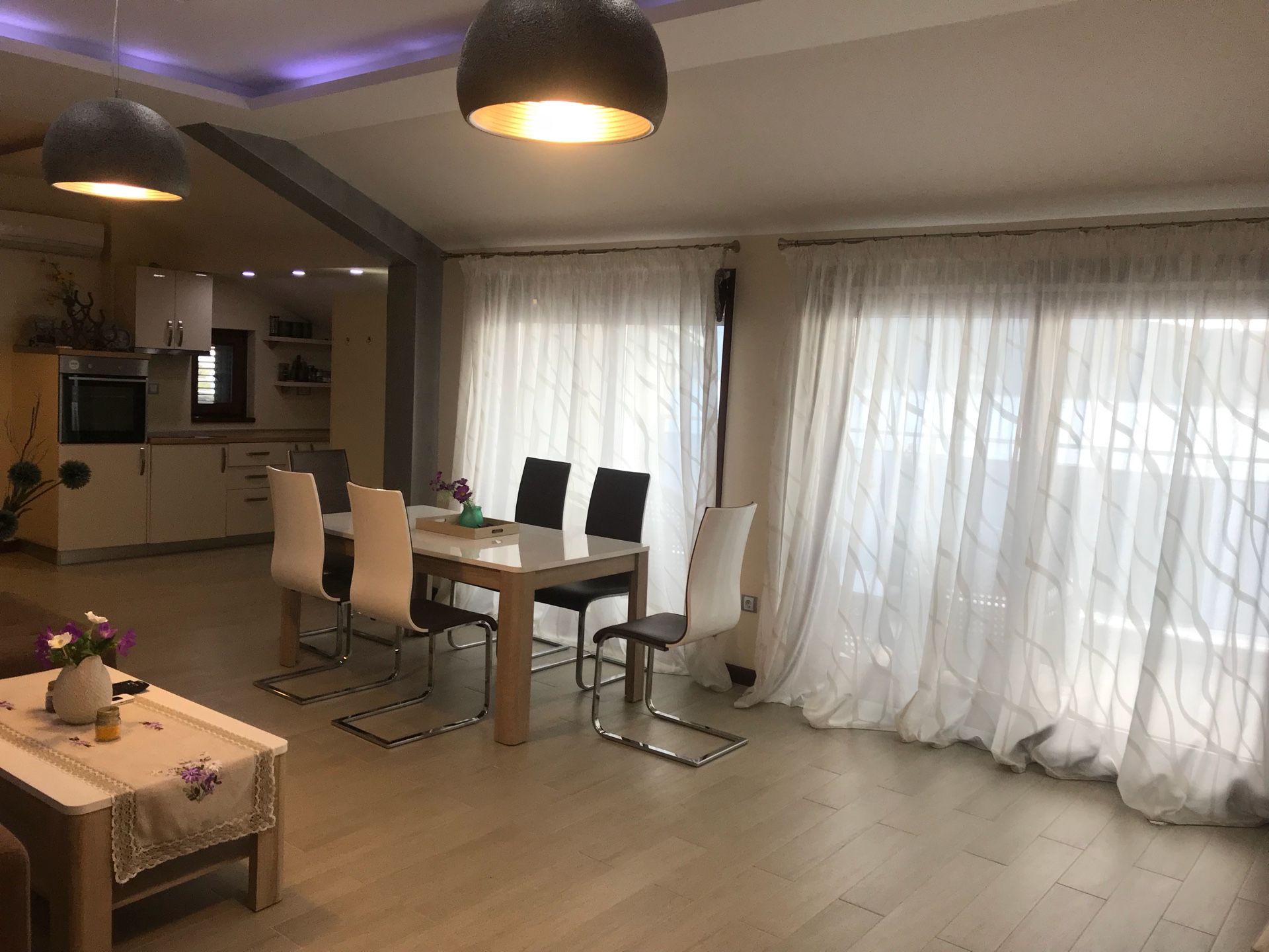 Nowoczesny salon z jadalnią w mieszkaniu, Herceg Novi, Czarnogóra: jasne meble, panoramiczne okna i kuchnia.
