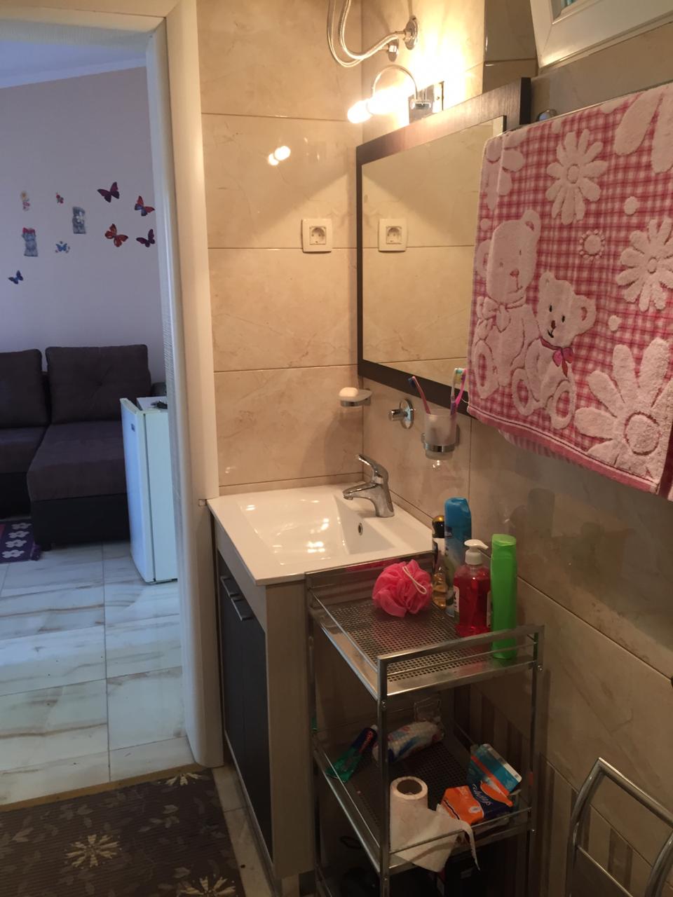 Badezimmer mit beigen Fliesen und Spiegel in einem Haus in Šušanj, Montenegro, Blick auf den Wohnbereich mit Sofa.