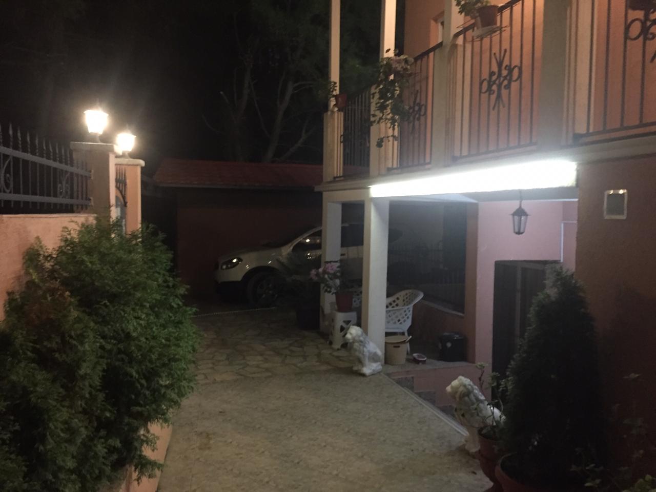 Zweistöckiges Haus in Shushan, Montenegro: Nachtansicht des privaten Grundstücks, des Parkplatzes und der beleuchteten Terrasse.