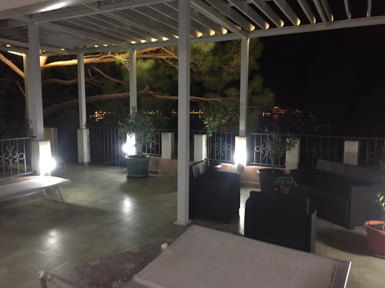 Abendterrasse mit Möbeln und Meerblick in einem Haus in Šušanj, Montenegro: gemütlicher Ruhebereich unter einem Vordach.