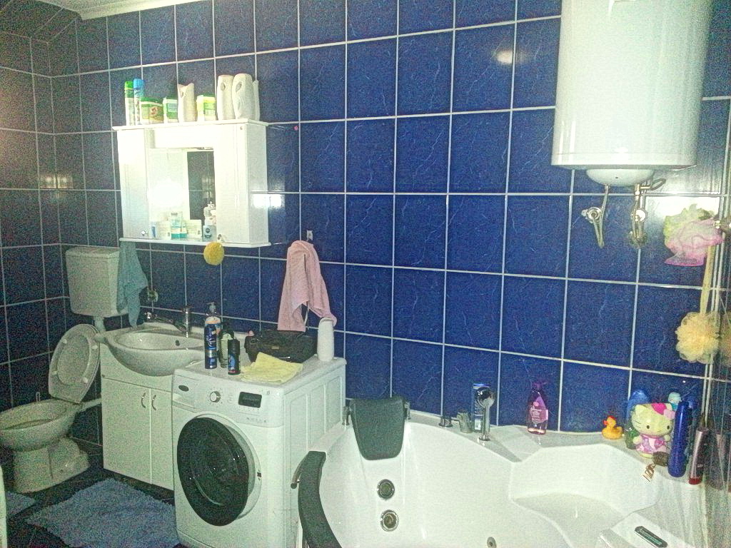 Kupatilo sa plavim pločicama, ugaonom kadom, veš mašinom i bojlerom u kući, Herceg Novi, Crna Gora.