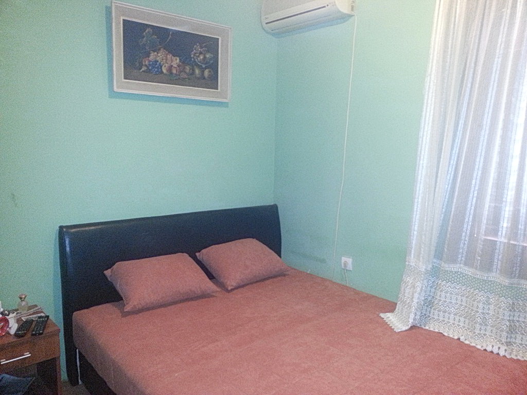 Spavaća soba u kući u Herceg Novom, Crna Gora: bračni krevet sa tamnim uzglavljem, klima-uređaj i slika na zidu.