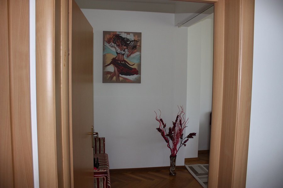 Innenansicht des Flurs in einer Wohnung in Budva, Montenegro: helle Wände, ein Bild mit einer Tänzerin und eine Bodenvase mit Dekoration.