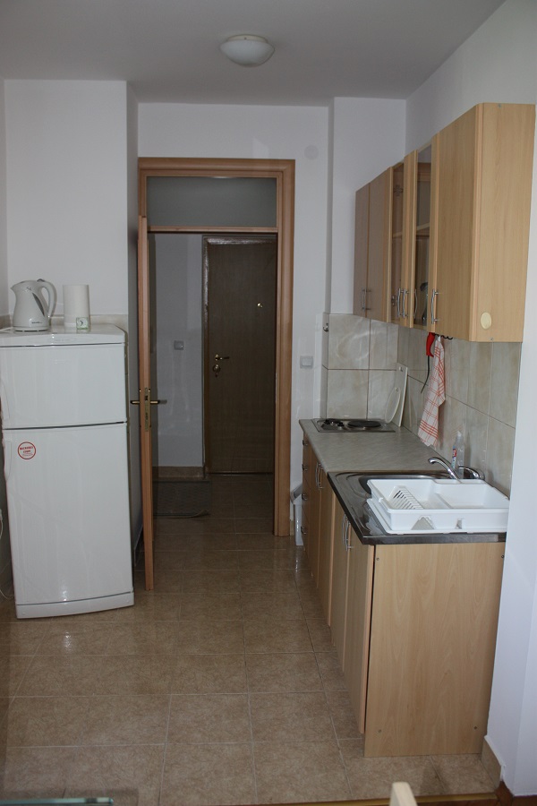 Kompakte Küche in einer Wohnung in Budva, Montenegro: helle Einbauküche, Herd, Kühlschrank und Fliesenboden.