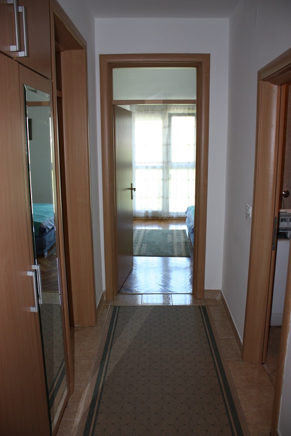 Flur mit Spiegelschrank in einer zum Verkauf stehenden Wohnung in Budva, Montenegro: Blick auf das helle Schlafzimmer mit Parkett.