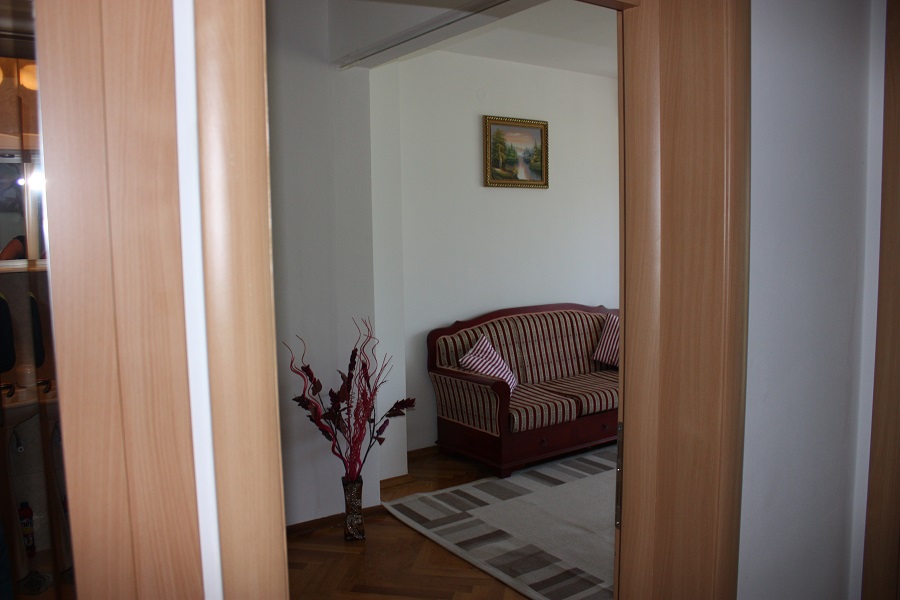 Innenansicht des Wohnzimmers mit gestreiftem Sofa und Parkett in einer zum Verkauf stehenden Wohnung in Budva, Montenegro.
