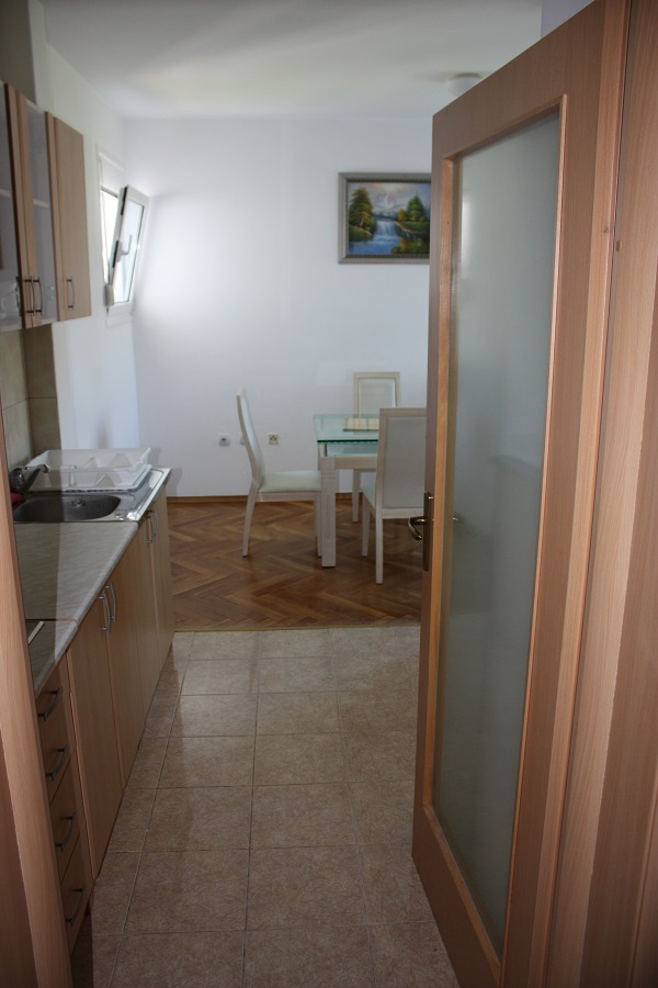 Küche mit Holz-Einbauküche und Essbereich in einer Wohnung in Budva, Montenegro: Fliesenboden und Parkett im Wohnzimmer.