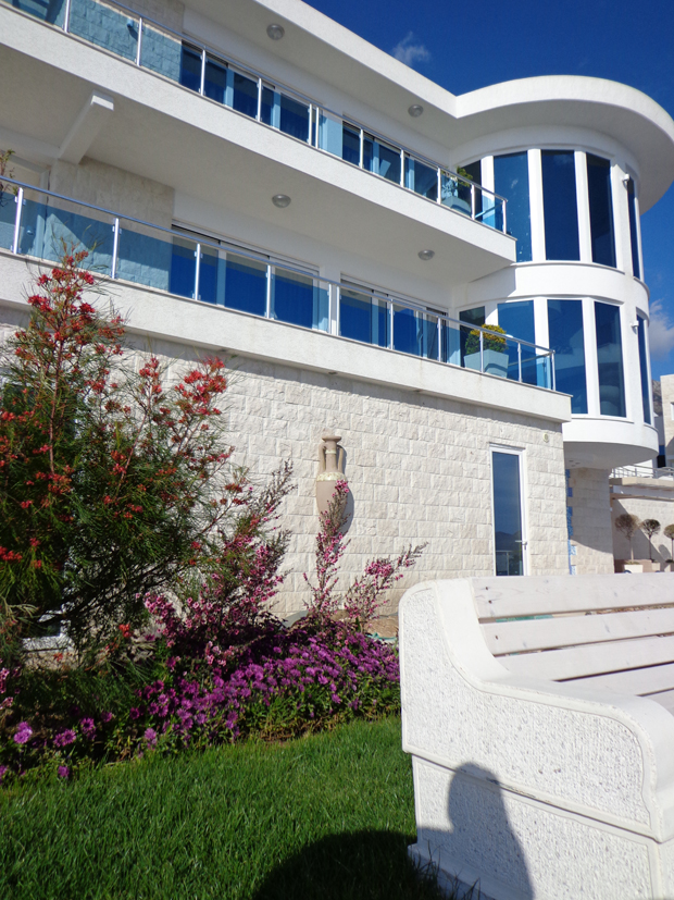 Savremena vila sa panoramskim prozorima i terasama u Dobrim Vodama, Crna Gora: pogled na fasadu i uređenu baštu.