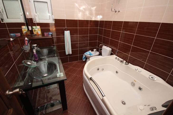 Dobri Vody, Karadağ’daki evde jakuzili ve cam lavabolu banyo. Kahverengi fayanslarla modern kaplama.
