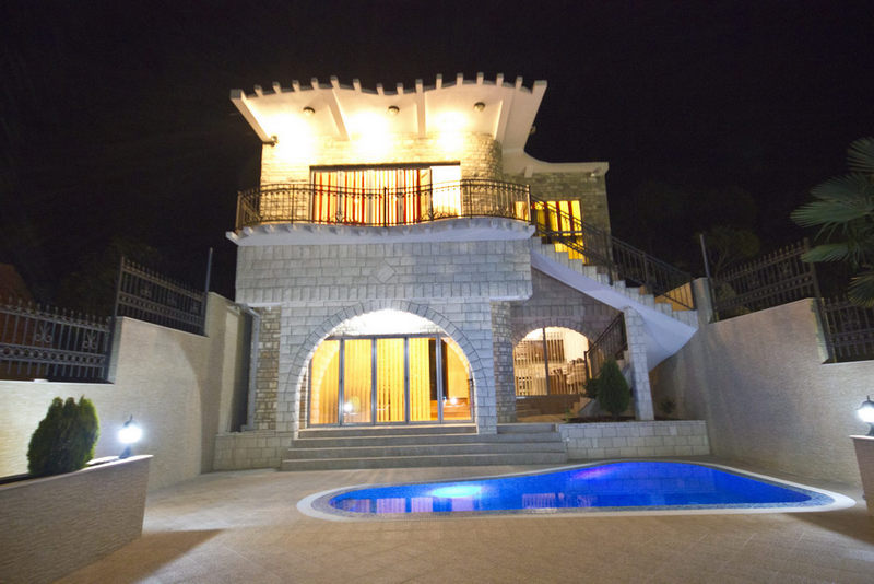Karadağ, Dobra Voda’da havuzlu ve aydınlatmalı iki katlı taş villa, geceleri evin cephe görünümü.