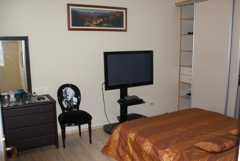 Schlafzimmer in einem Haus in Bigovo, Montenegro: Doppelbett, Kommode, Designerstuhl und TV-Bereich mit modernen Möbeln.