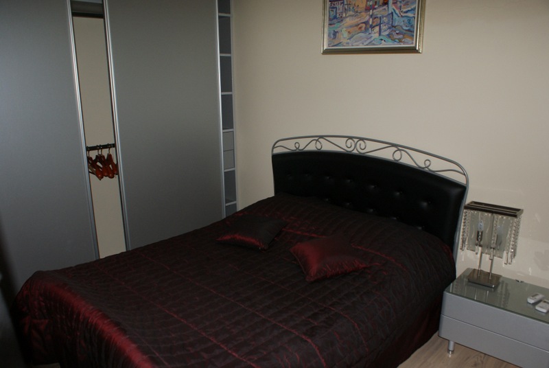 Schlafzimmer in einem Haus in Bigovo, Montenegro: Doppelbett mit dunkler Tagesdecke, Einbauschrank und Nachttisch.