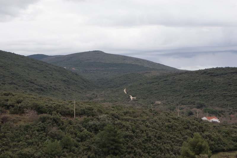 Panoramablick auf grüne Hügel und ein Landhaus im Ort Bigovo, Montenegro, mit einer malerischen Waldstraße.