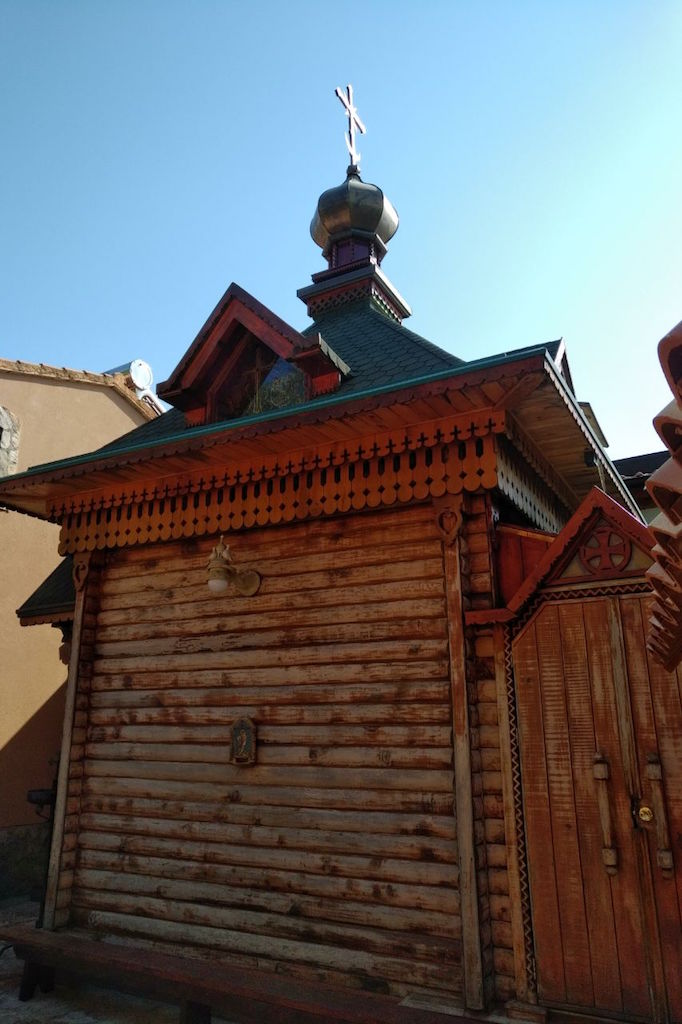 Drvena kapela u ruskom stilu na parceli u Svetom Stefanu, Crna Gora: pogled na brvnaru sa kupolom i krstom.