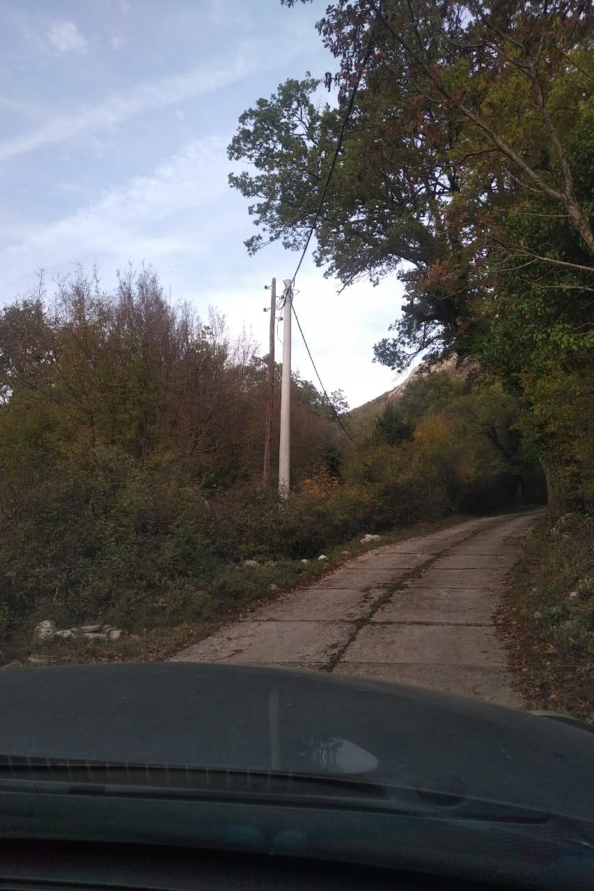 Zemljani put do zemljišne parcele u Svetom Stefanu, Crna Gora, okružen gustim šumama i planinama.