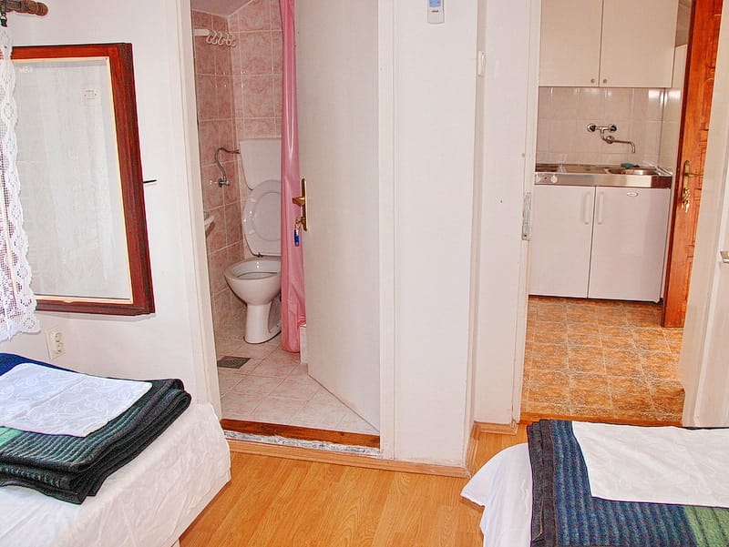 Intérieur d'une chambre avec salle de bain et kitchenette dans une maison, Igalo, Monténégro. Appartement compact meublé et équipé.