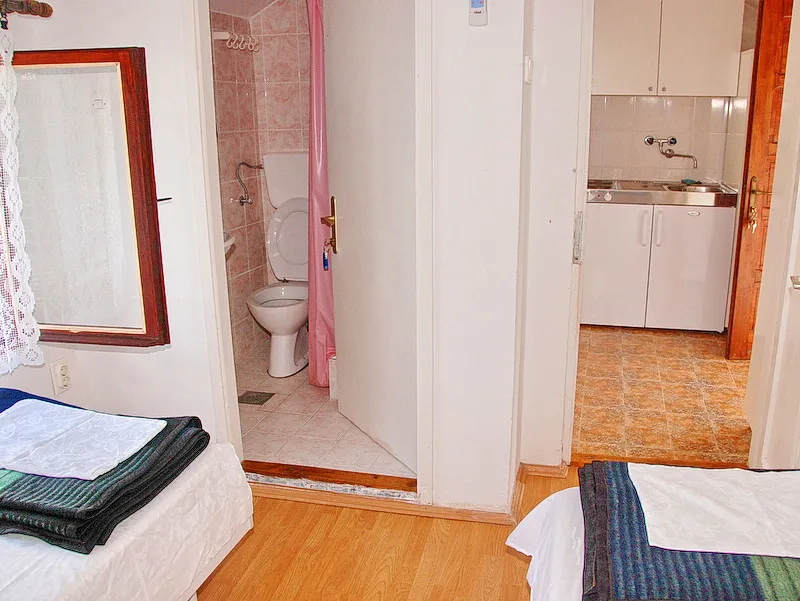 Intérieur d'une chambre avec salle de bain et kitchenette dans une maison, Igalo, Monténégro. Appartement compact meublé et équipé.