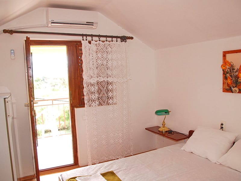 Chambre dans une maison à Igalo, Monténégro : lit double, accès au balcon, climatisation et décoration murale.