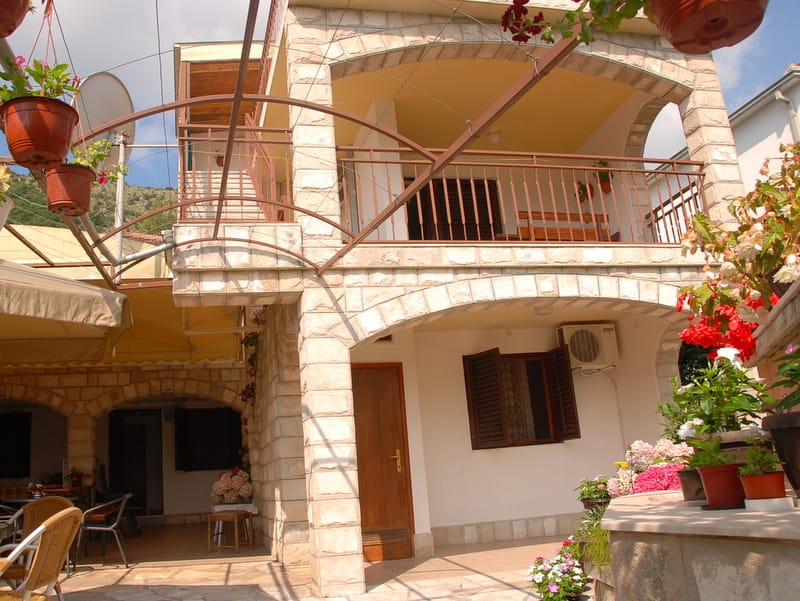 Maison en pierre de deux étages avec terrasse et jardin à Igalo, Monténégro : vue extérieure de la façade avec éléments en arc.
