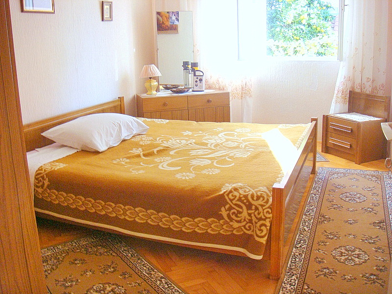 Cozy bedroom with wooden furniture and a view of the garden in a house for sale, Baošići, Montenegro.