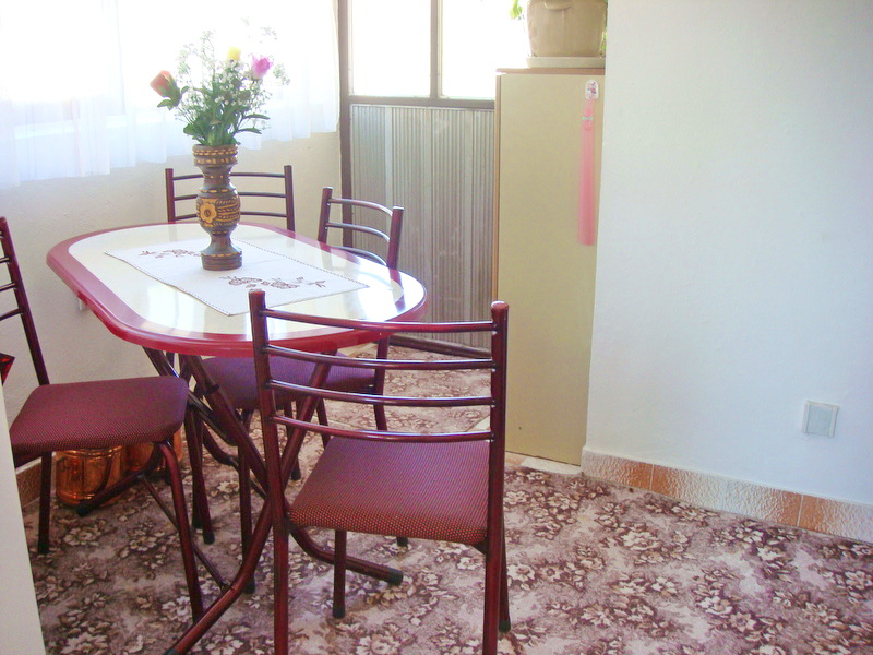 Dining area with a red table and chairs in a house for sale, Baošići, Montenegro: a cozy kitchen with carpet flooring.
