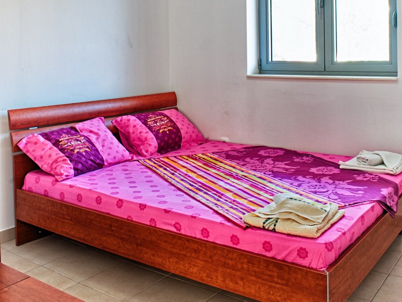 Schlafzimmer mit Doppelbett in einer Wohnung in Petrovac, Montenegro: heller Raum mit Fliesen und Fenster.